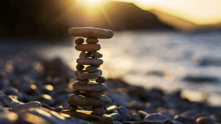 Steinturm im Sonnenlicht am Wasser – Symbol für Balance, Achtsamkeit und Energiearbeit im Allgäu | SeelenSanft